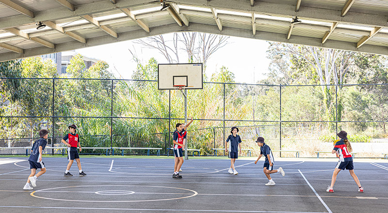 Students playing basketball on the school basketball court at Our Lady of the Angels Primary School Rouse Hill