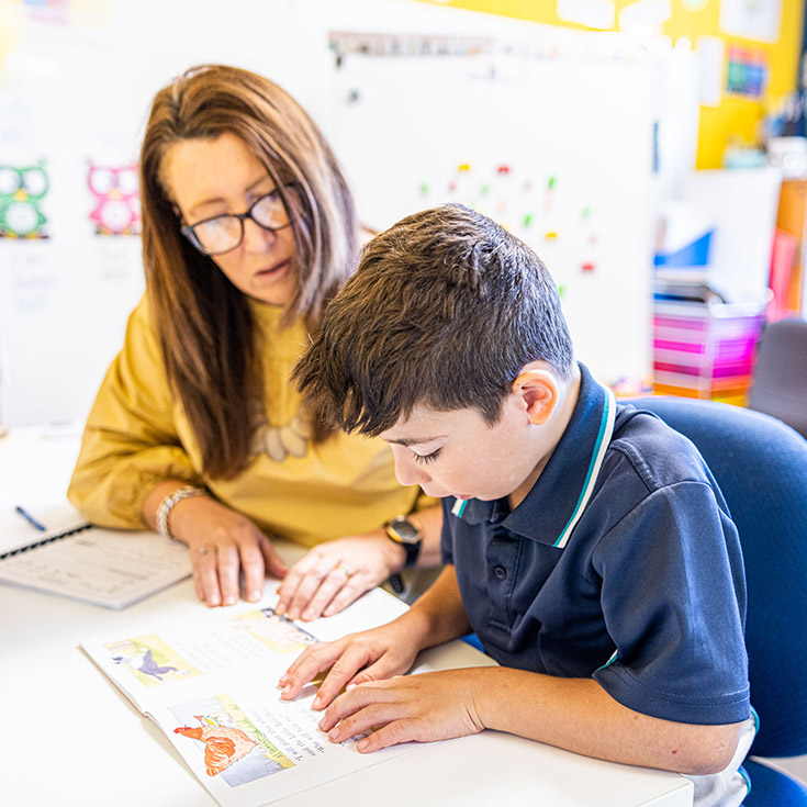 Student learning to read with his teacher at Our Lady of the Angels Primary School Rouse Hill